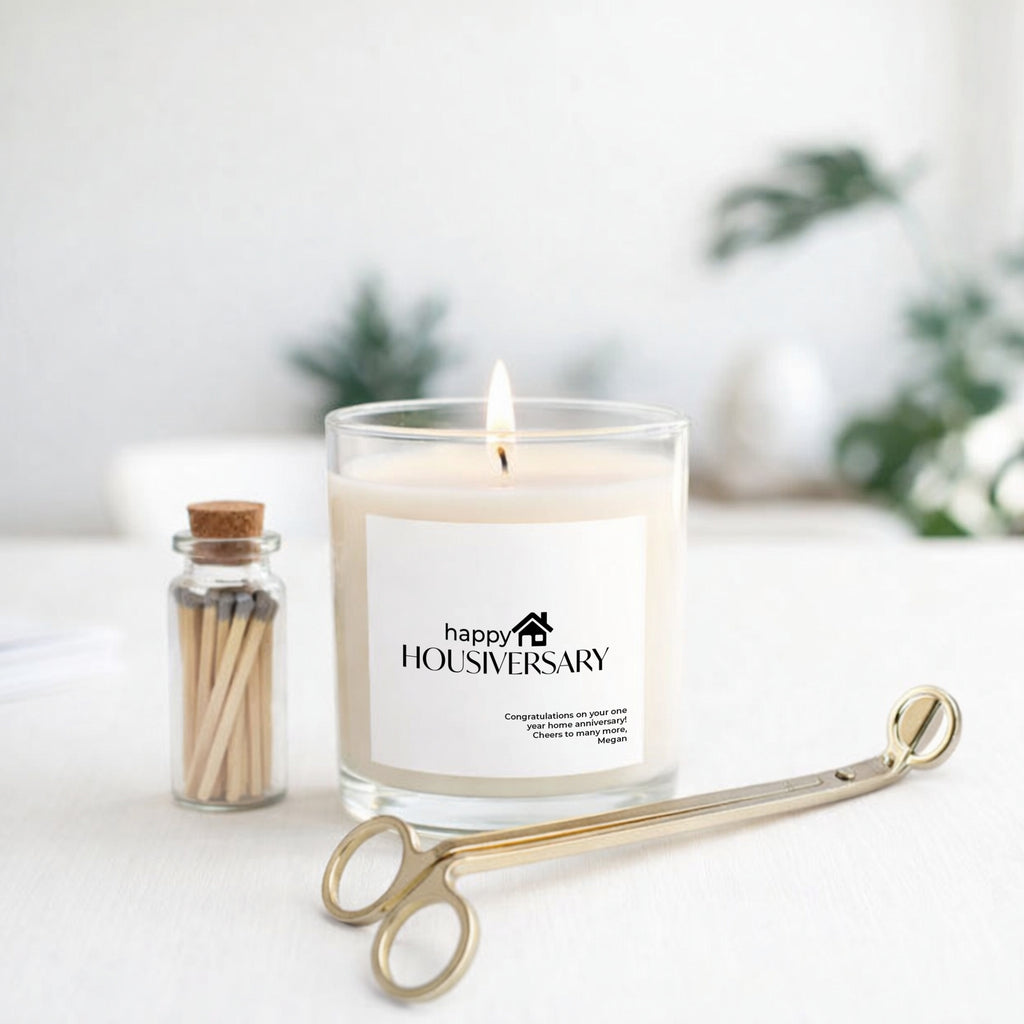 Home Anniversary Gift Happy Housiversary Candle featuring a soy candle, matches jar, and gold candle trimmer.